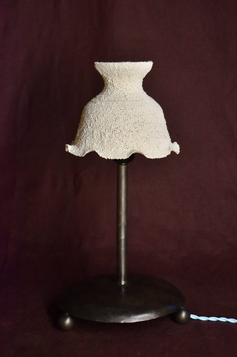 Small lamp with a white ruffled recycled-plastic shade on a dark metal stand