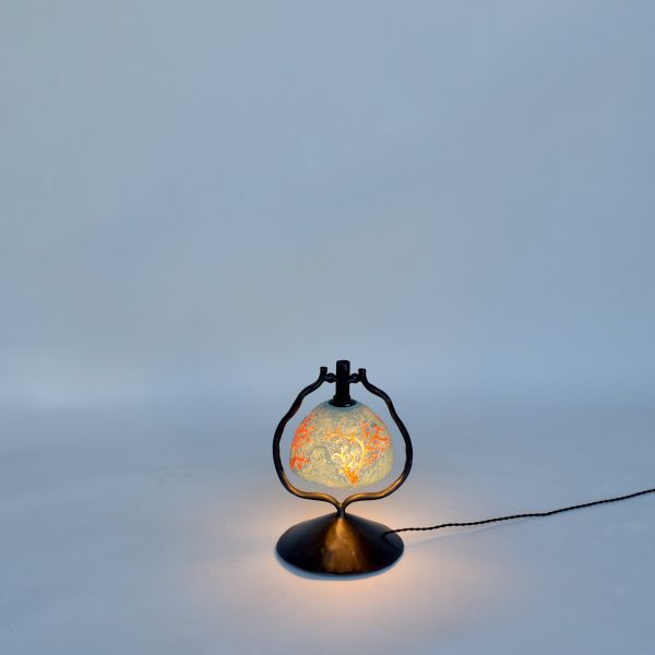 Peloria table lamp lit, black steel frame holding a recycled-plastic shade
